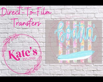 May include: A Direct-To-Film Transfer design featuring the word "boatin'" in a cursive script above a light blue boat illustration. The design includes a pink logo with the text "Kate's EST. 2022" and a floral wreath.