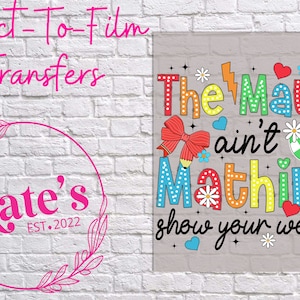 May include: A colorful graphic design with the text "The Math ain't Mathin' show your work". The design features a red bow, a pencil, a green apple, and a rainbow-colored background.