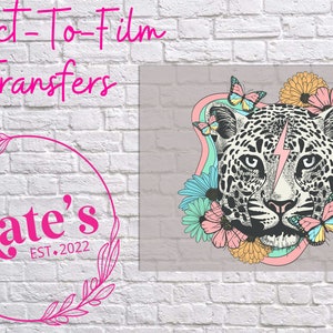 Könnte beinhalten: Direkt-zu-Film-Transfers mit einem Leoparden-Design mit einem rosa Blitz, umgeben von Blumen und Schmetterlingen. Das Bild enthält den Text "Kate's EST. 2022" in einem rosa Blumenkranz.