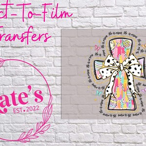 May include: A colorful cross with a black and white polka dot bow and the text "He is risen" repeated around the cross. The background is a light gray.