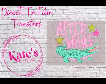 May include: Direct-to-film transfers featuring a teal alligator with the words "AFTER WHILE" in pink, accented by yellow and pink stars. The image also includes a pink circular logo with the text "Kate's EST. 2022".