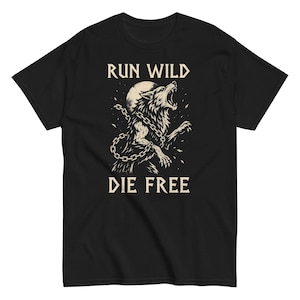 Puede incluir: Camiseta negra con un diseño de lobo aullando y el texto "RUN WILD DIE FREE". El lobo está encadenado, con una luna llena de fondo. El diseño es de estilo vintage, inspirado en tatuajes.