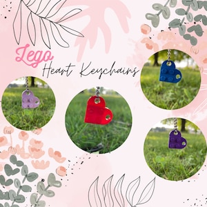 May include: Lego heart keychains in purple, red, and blue. The keychains are hanging from a chain and are on a green grassy background.