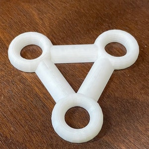 Puede incluir: Conector de plástico blanco de tres anillos con tres aberturas circulares.