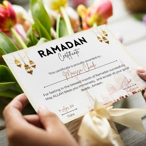 May include: A certificate with a gold and white design, featuring a mosque and lanterns. The text "RAMADAN Certificate" is at the top, and the text "This certificate is proudly awarded to: Maissa Chad" is below. The text "For fasting in the blessed month of Ramadan successfully May ALLAH bless you immensely, and accept all your good deeds, Ameen." is in the middle of the certificate. The text "11 Apr 2004" is at the bottom of the certificate.