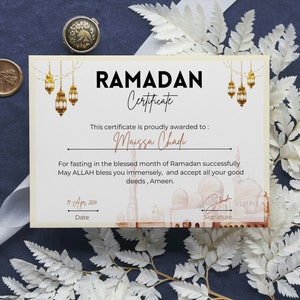 May include: A certificate with a gold and white design, featuring a mosque and lanterns. The text reads "RAMADAN Certificate" and "This certificate is proudly awarded to: Maissa Chad". The date is "11 Apr 2004".