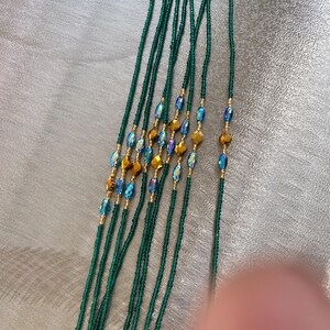 K&ouml;nnte beinhalten: Ein Satz gr&uuml;ner Perlen f&uuml;r die Taille mit schillernden blauen und goldenen Akzenten.
