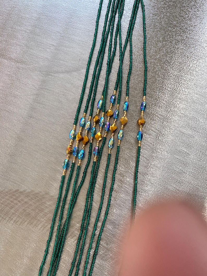 K&ouml;nnte beinhalten: Ein Satz gr&uuml;ner Perlen f&uuml;r die Taille mit schillernden blauen und goldenen Akzenten.