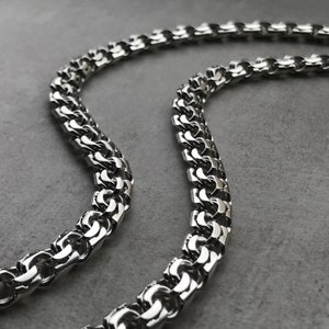 May include: A silver chain necklace with a box chain design. The chain is made of metal and has a shiny finish.