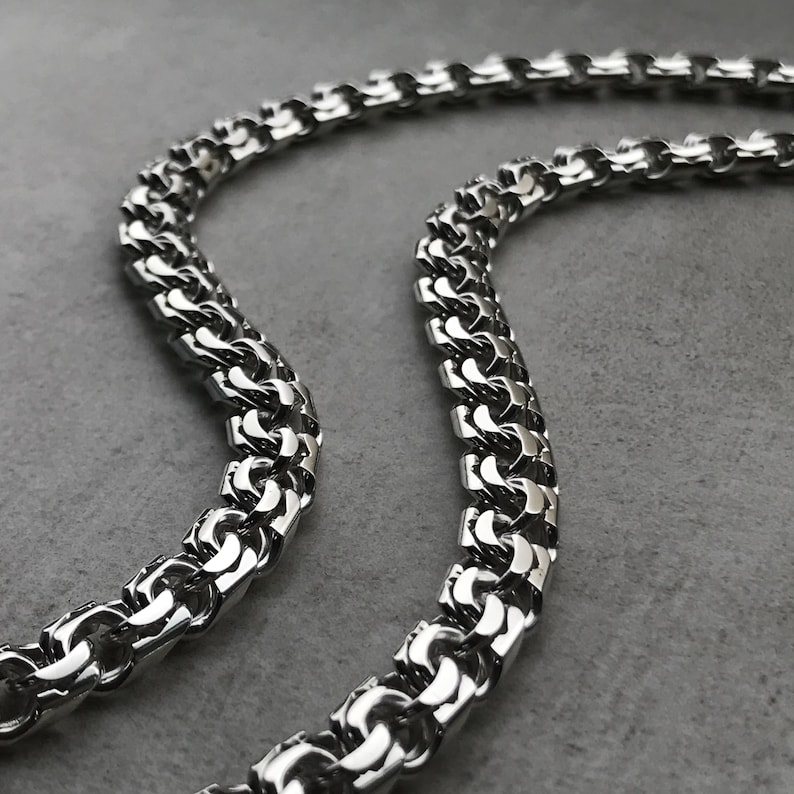 May include: A silver chain necklace with a box chain design. The chain is made of metal and has a shiny finish.