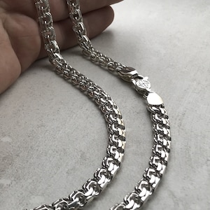 May include: A silver chain necklace with a box chain design. The chain is made of interlocking square links.