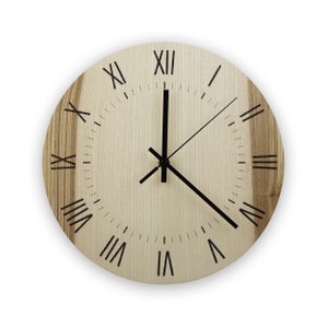 Könnte beinhalten: Eine runde Holzuhr mit römischen Ziffern und schwarzen Zeigern. Das Zifferblatt der Uhr ist hellbraun mit einer Holzmaserung.
