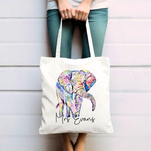 May include: White canvas tote bag with a colorful watercolor illustration of an elephant. The text "Mrs. Evans" is printed in black below the elephant.
