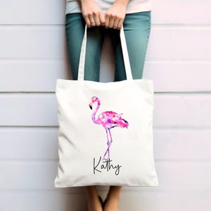 May include: White tote bag featuring a pink flamingo illustration and the name "Kathy" printed on the front.