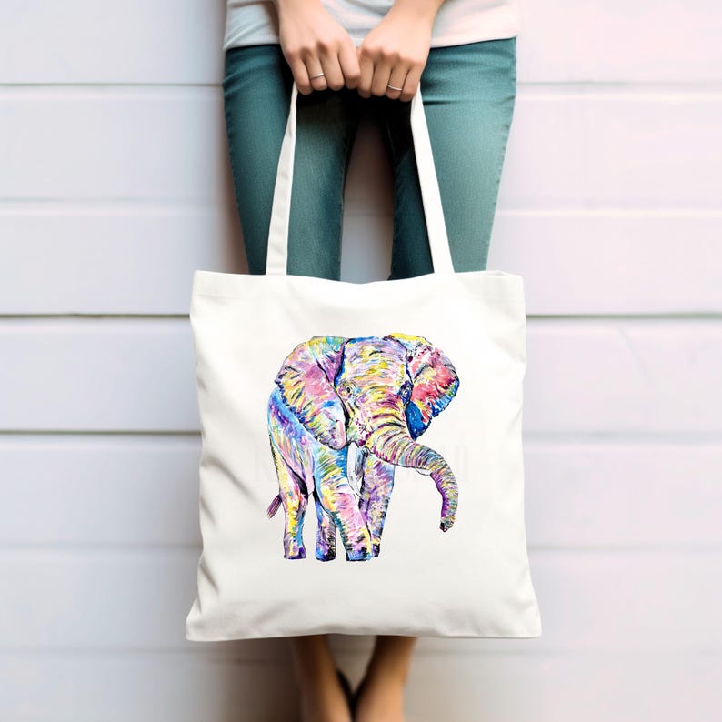 May include: A white tote bag with a colorful illustration of an elephant. The elephant is painted in shades of pink, blue, yellow, and green.