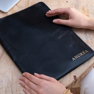 May include: A black leather portfolio with the name "ANDREA" embossed in gold lettering.