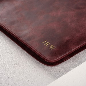 May include: A burgundy leather laptop sleeve with gold embossed initials "JRW".