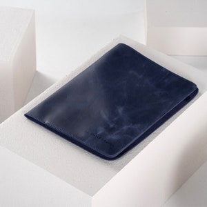 May include: A dark blue leather notebook cover with a subtle textured finish.