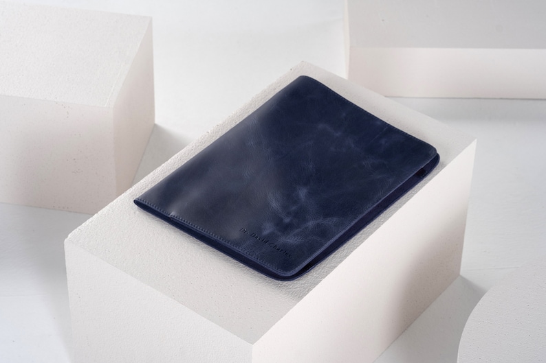 May include: A dark blue leather notebook cover with a subtle textured finish.