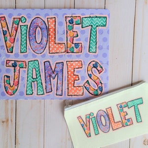 May include: A purple and white jigsaw puzzle with the names "VIOLET" and "JAMES" in colorful letters. A yellow pouch with the name "VIOLET" in colorful letters.