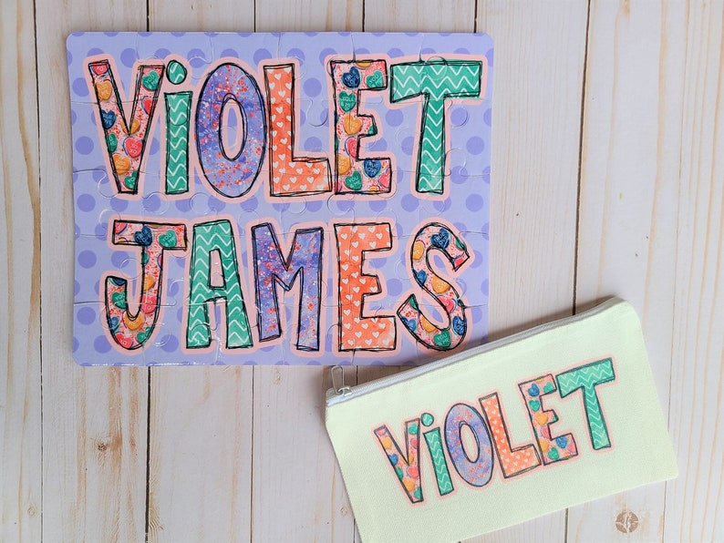 May include: A purple and white jigsaw puzzle with the names "VIOLET" and "JAMES" in colorful letters. A yellow pouch with the name "VIOLET" in colorful letters.