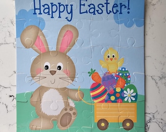 May include: A colorful Easter-themed puzzle featuring a cartoon bunny and chick. The puzzle has the words "Happy Easter!" and the name "Eddie". The bunny is holding a rope attached to a wagon filled with Easter eggs and carrots.