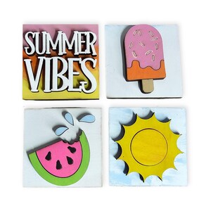 May include: Four square wooden plaques featuring summer themes. One plaque displays the white text SUMMER VIBES on a gradient background. The others show a pink popsicle, a slice of watermelon with blue water droplets, and a bright yellow sun.