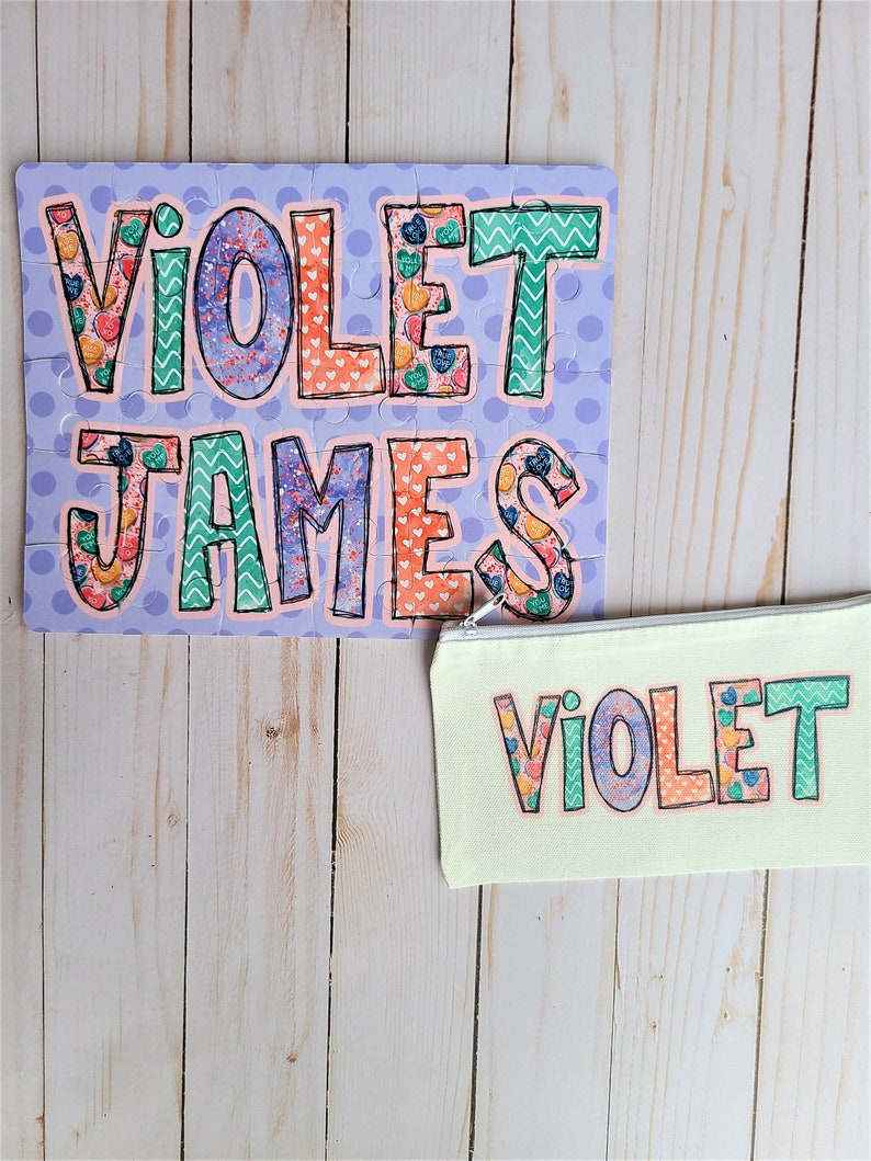 May include: A personalized puzzle with the names "Violet James" in colorful patterned letters on a purple background. A matching zippered pouch with the name "Violet" in colorful patterned letters on a light green background.