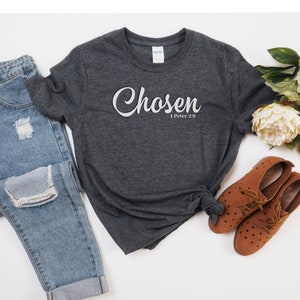 Könnte beinhalten: Ein dunkelgraues T-Shirt mit dem Wort "Chosen" in weißer Schrift und dem Text "1 Peter 2:9" in weiß darunter.