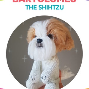 Puede incluir: Un perro Shih Tzu de crochet blanco llamado Bartolomeu, sentado con las patas cruzadas. El perro tiene pelo marrón en la cabeza y la espalda. El perro está sentado en una mano, y el fondo es gris claro con signos más blancos.