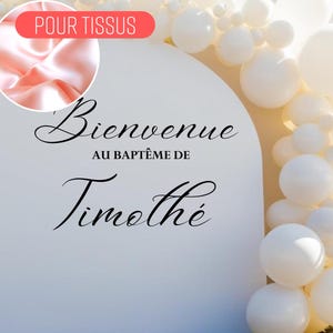 Op de afbeelding: Een wit bord met de tekst "Bienvenue au baptême de Timothée" in zwarte cursieve letters. Het bord is versierd met een witte ballonnenboog.