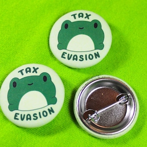 May include: Three round buttons with a green frog design and the text "Tax Evasion". One button is a blank back.