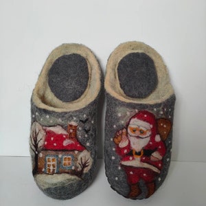 May include: A pair of gray wool slippers with a winter scene design. One slipper features a house with a red roof and a snowy landscape. The other slipper features Santa Claus with a bag of gifts.