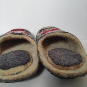 May include: A pair of gray wool slippers with a colorful design. The slippers have a soft, fuzzy lining and a gray felt sole.