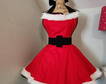 May include: Red and white Christmas apron with a black belt and white fur trim. The apron is on a dress form.
