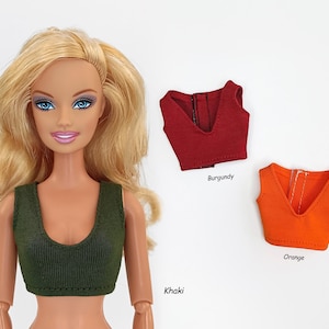 May include: Three sleeveless crop tops in different colors: khaki, burgundy, and orange. The tops are made of a ribbed fabric and have a V-neckline.