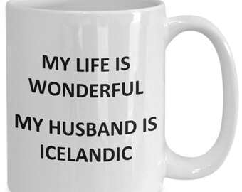 May include: White ceramic mug with the text "MY LIFE IS WONDERFUL MY HUSBAND IS ICELANDIC" in black. The mug has a curved handle and a glossy finish. A simple, everyday coffee mug. Ideal for tea or coffee.