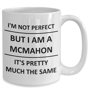 May include: White ceramic mug with a curved handle. The mug features black text that reads "I'M NOT PERFECT BUT I AM A MCMAHON IT'S PRETTY MUCH THE SAME". A humorous and personalized gift.