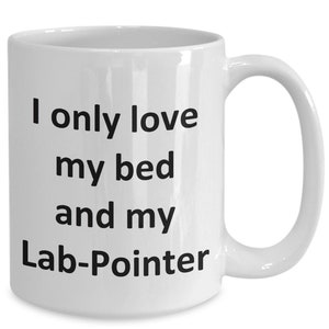 以下が含まれることがあります： 白いセラミック製のコーヒーカップで、黒い文字で「ベッドとラブポインターしか愛してない」と書かれています。