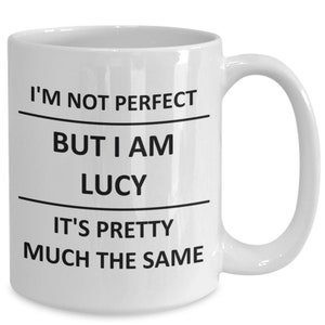 May include: White ceramic coffee mug with black text that reads "I'm not perfect but I am Lucy it's pretty much the same".