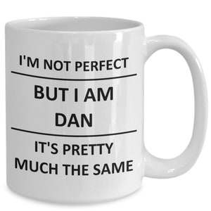 Peut inclure: Une tasse à café en céramique blanche avec du texte noir qui dit "Je ne suis pas parfait mais je suis Dan c'est à peu près la même chose".