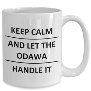 Peut inclure: Une tasse à café en céramique blanche avec du texte noir qui dit "Keep Calm and Let the Odawa Handle It."