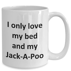 May include: White ceramic coffee mug with black text that reads "I only love my bed and my Jack-A-Poo."