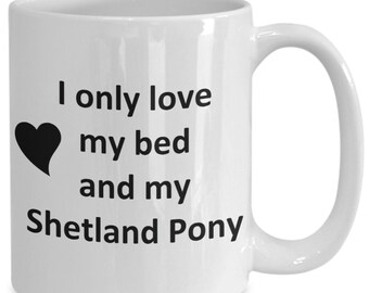 May include: White ceramic coffee mug with black text that reads "I only love my bed and my Shetland Pony" with a black heart symbol.