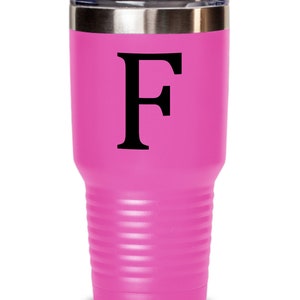 May include: A pink stainless steel tumbler with a black letter "F" on the front. The tumbler has a double-wall insulated design and a lid.
