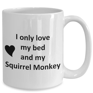 May include: White ceramic coffee mug with black text that reads "I only love my bed and my Squirrel Monkey". A black heart is to the left of the text.