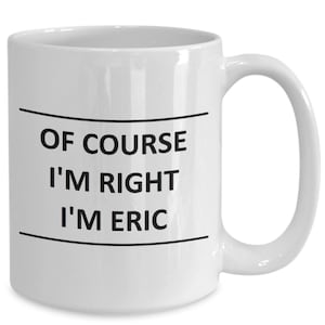 May include: White ceramic mug with a curved handle. The mug features the text "OF COURSE I'M RIGHT I'M ERIC" in black, centered between two black lines. The mug is designed for beverages.