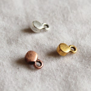 Pu&ograve; includere: Tre ciondoli in metallo di diversi colori: argento, oro e rame. Ogni ciondolo &egrave; un piccolo cerchio con un anello sul lato.