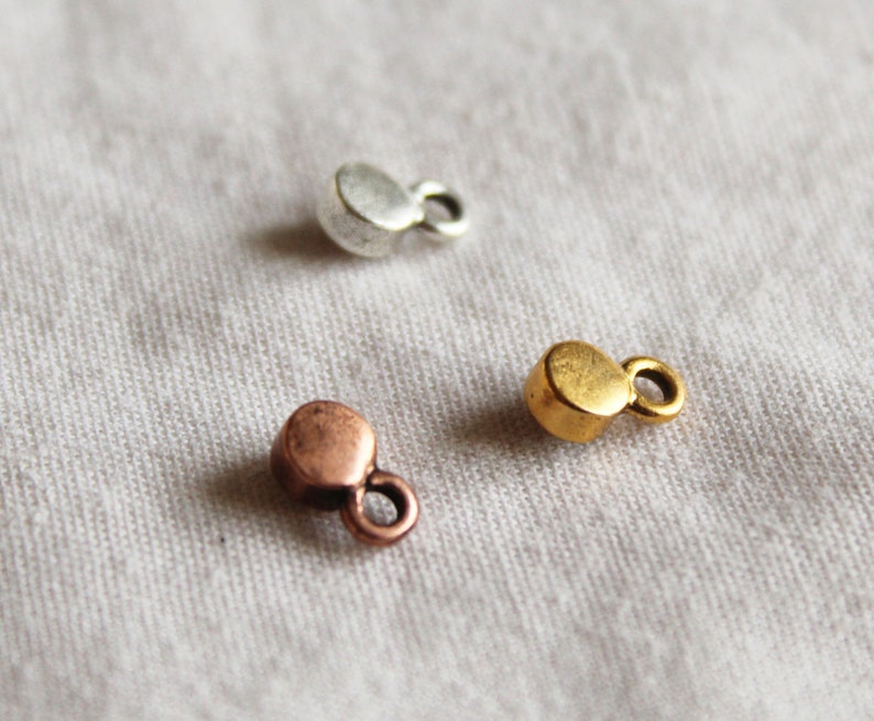 Pu&ograve; includere: Tre ciondoli in metallo di diversi colori: argento, oro e rame. Ogni ciondolo &egrave; un piccolo cerchio con un anello sul lato.