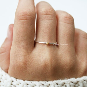 K&ouml;nnte beinhalten: Ein schlichter Silberring mit einem kleinen, runden, hellbraunen Edelstein. Der Ring wird an einem Finger getragen.